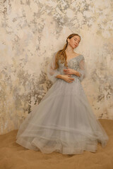 a girl in a dress on the sand against a shabby wall