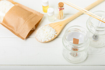 Set for homemade natural white eco-friendly soy wax candles in glass, wick, aroma oil and dried flowers on white wood. Hobby, business. Making candles with your own hands. Vegan product. Copy space.