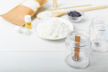 Set for homemade natural white eco-friendly soy wax candles in glass, wick, aroma oil and dried flowers on white wood. Hobby, business. Making candles with your own hands. Vegan product. Copy space.