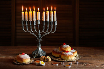 Jewish holiday Hanukkah with menorah (traditional Candelabra), donuts and wooden dreidels (spinning top), chocolate coins.