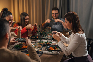 Friends use their smart phones to take pictures of delicious and nicely served dinner