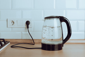 Transparent electric kettle with boiling water on the table in the kitchen.Kettle for boiling water...