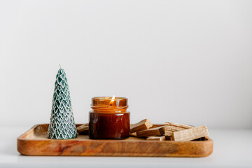 Merry Christmas decoration concept with burning candles and festive decor, christmas trees on light white background. Cozy home. Space for text.