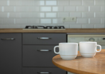 Cups with hot drinks on the table on the background of the kitchen in the house. Tea coffee. Warming drink. Breakfast time.Tea drinking. Side view, space for text.