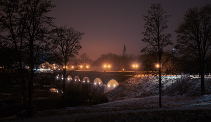 Old brick bridge in lantern lights. Atmospheric view to the small town in the night. Winter
