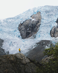 Hiker in yellow jacket in front of majestic glacier in Norway, Buerbreen glacier