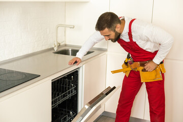 Man repairing a dishwasher with tools
