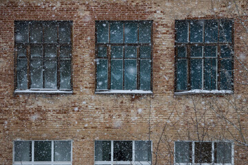 Heavy snowfall on the background of the old brick facade of the building with windows.