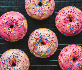 Close up of vanilla cake donuts with pink icing and sprinkles.