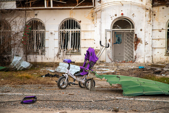 War in Ukraine. Baby carriage against the background of a broken house.