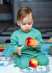 Fototapeta premium Cute baby boy eating apple at home. Healthy child nutrition