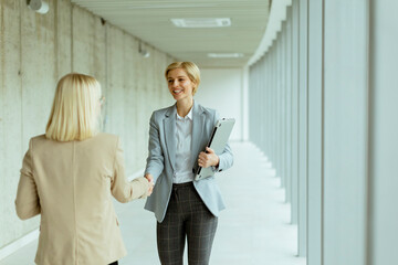 Business women handshaking in the office corridor
