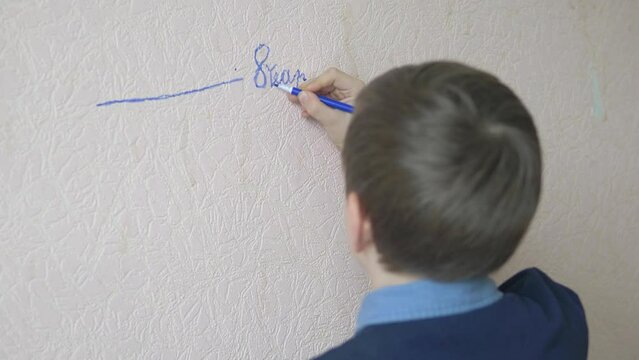 the boy draws on the wall a growth mark at 8 years old, selective focus. children's growth, measuring the growth at home near the wall. the boy dreams of growing tall