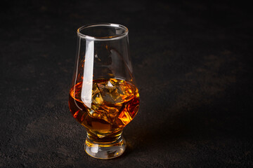 Whiskey with ice in a glass on a dark background.