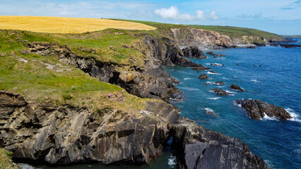 Farm fields on the rocky shore of the Celtic Sea, south of Ireland, County Cork. Beautiful coastal area. Turquoise waters of the Atlantic. Picturesque stone hills. Drone photo.