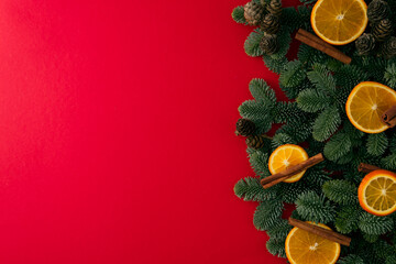 Green branches of a Christmas tree with a festive decor on a red background copy space 