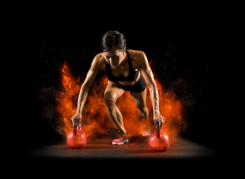 Woman workout with red kettlebell. Fire background