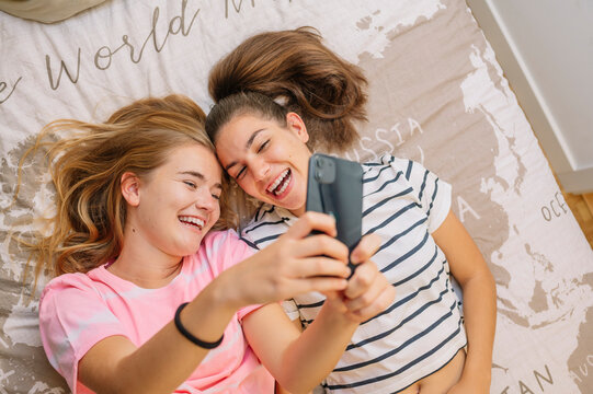 Two young girls taking selfies in their room.