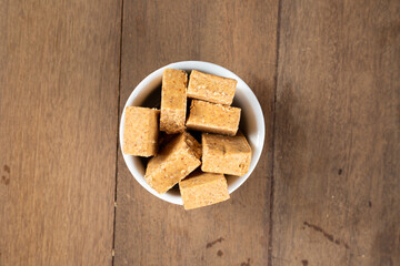 Pacoca is a Brazilian Peanut Sweet. on a white bowl on a wooden deks. Top view