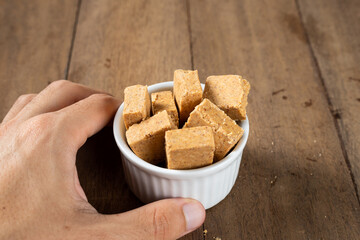 Man's Hand Holding a bowl full of Brazilian Peanut Sweet called Paçoca