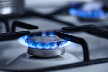 Gas stove flame. Blue flame from a gas stove burner. Close-up shot of a blue fire from a home cooking stove. Photo of a blue flame from a kitchen gas stove with propane gas.