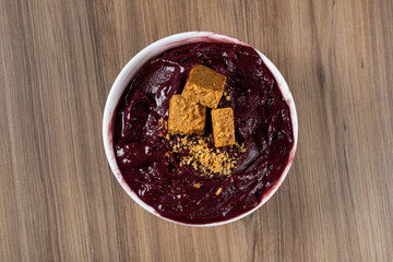 White Bowl of Brazilian Frozen Açai Berry With Paçoca. on a wooden desk. Top view