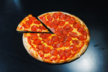 Sliced pizza with sausage, tomato sauce, mozzarella, onion and dough rim, topped with cream cheese on a black background