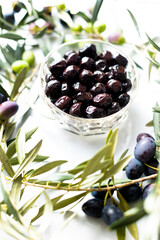ripe olives lie in a plate. olive branches