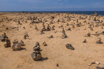 View of Atlantic Ocean coastline decorated with small pyramids made of stones. Aruba, North side.