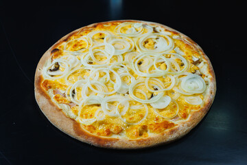 Sliced pizza with onion and meat, tomato sauce, mozzarella, onion and edge of dough, filled with cream cheese on a black background