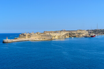 Fototapeta na wymiar The entrance to the Grand Harbour in Malta protected by Fort Ricasoli. In front of the fort is the Ricasoli Breakwater and its lighthouse.