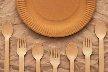 Wooden forks and spoons and paper plate on crumpled paper
