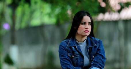 Pensive contemplative young woman sitting outside at park