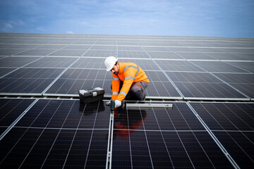 Professional worker installing solar panels for sustainable energy power plant.