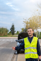 Caucasian man in yellow reflective vest hitchhiking on the street