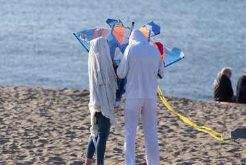 Two people building a kite and preparing to fly it