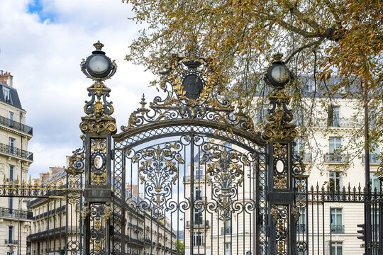 Paris, in the beautiful parc Monceau, the golden wrought iron grid, with typical buildings in background 
