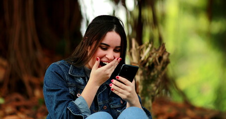 Happy woman receiving good news message on smartphone outdoors