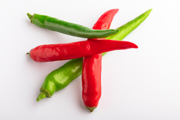 A bunch of green and red chili peppers on a white background. Close-up