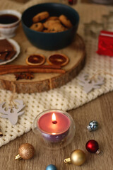 Fototapeta premium Various Christmas decorations, cup of tea or coffee, sweets, small presents, knitted blanket and candles. Selective focus.