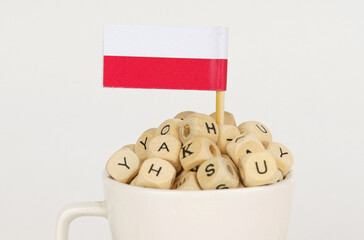 The flag of Poland sticks out of a cup with cubes on which letters are depicted