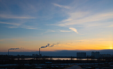 coal power plant high pipes with black smoke moving up polluting atmosphere at sunset in Kyiv city of Ukraine.