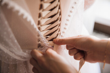 female hands lace up the bride's dress, close-up