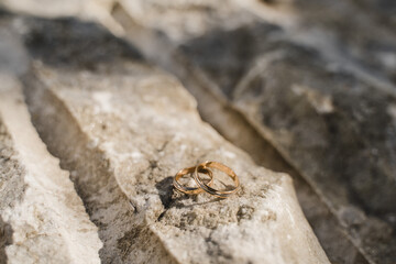 golden wedding rings lie on a stone surface