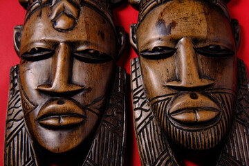 Vintage wooden African masks on red background, top view
