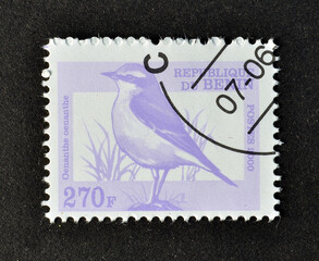 Cancelled postage stamp printed by Benin, that shows Northern Wheatear (Oenanthe oenanthe), circa 2000.