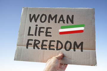 Cardboard sign with slogan held up in hand, Woman life freedom,