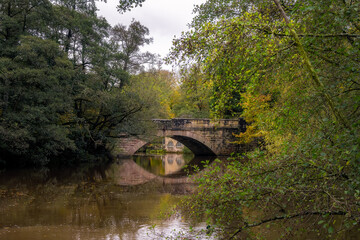 Fototapeta na wymiar Walking along the river Derwent in autumn, view of New bridge and the Shuttle house, Derbyshire, England