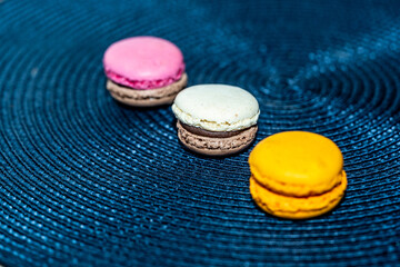 Colorful French or Italian macaron stack on blue background. Macarons or macaroons is French dessert served with afternoon tea or coffee break.
