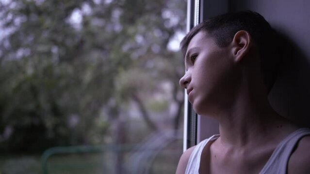 portrait of a sad boy looking out the window, loneliness, thinking about, steadicam shot